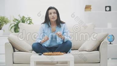 慢点。 一个年轻的女人正在打开电视节目，而坐在沙发上。 她在吃披萨。 <strong>好吃</strong>-<strong>好吃</strong>。 4K.